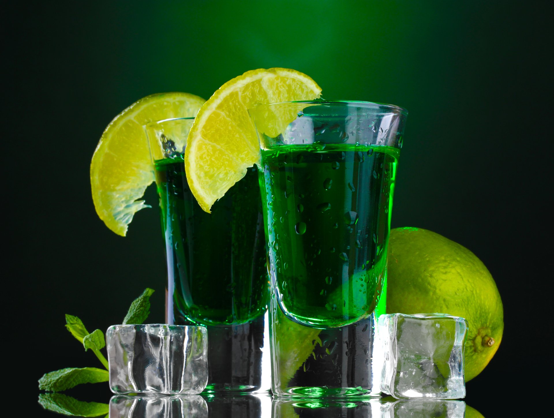 Close-up of two green cocktails with lime wedges on ice, captured in stunning 8K Ultra HD for PC desktop wallpaper and background.