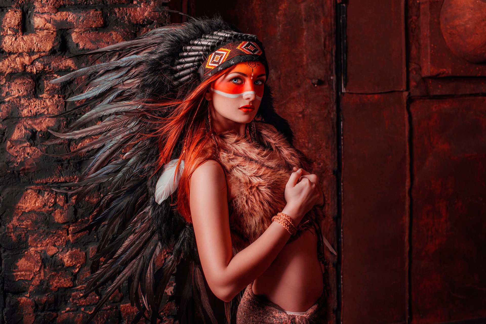 HD desktop wallpaper featuring a Native American woman model wearing a traditional feathered headdress and tribal face paint against a rustic background.