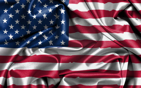 A high-definition desktop wallpaper featuring the American flag, beautifully displayed with flowing fabric textures that emphasize its vibrant colors and iconic design.