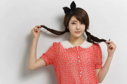 An Asian woman with a plait hairstyle poses confidently against a white background. She wears a red patterned dress with a white collar and black bow headband. HD desktop wallpaper and background.