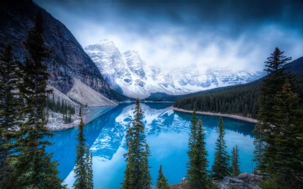 A stunning view of Moraine Lake in Banff National Park, showcasing the reflection of the Valley of Ten Peaks in the vibrant blue water, surrounded by lush evergreens and majestic mountains.