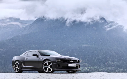 Black Chevrolet Camaro SS parked on a snowy surface with misty mountains and clouds in the background, shown in 4K Ultra HD as a PC desktop wallpaper.