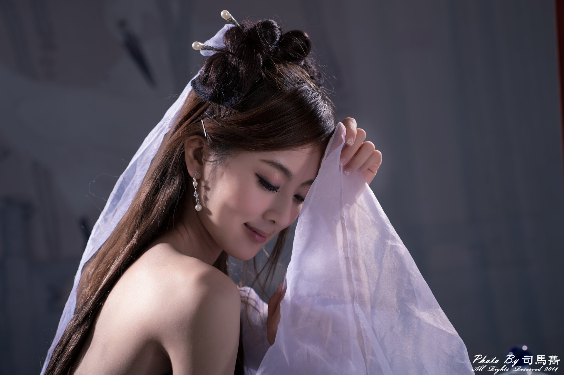 Smiling woman with hairpin and dangling earrings, partially draped in sheer fabric, elegant hair‑dress and soft lighting — 4K Ultra HD PC desktop wallpaper.