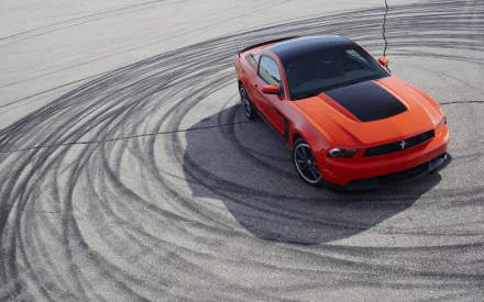 A striking orange Ford Mustang Boss 302 showcases its power, surrounded by tire marks on the asphalt, making it an impressive HD desktop wallpaper and background for car enthusiasts.
