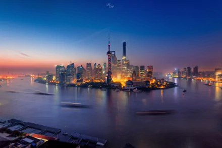 A stunning HD image of the Oriental Pearl Tower and Shanghai skyline at twilight, showcasing the vibrant lights reflecting on the water in this man-made marvel.