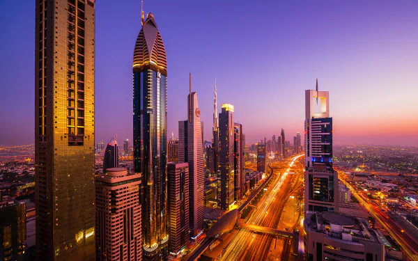 HD desktop wallpaper of Dubai cityscape at twilight along Sheikh Zayed Avenue, man-made skyline of skyscrapers including Rose Tower, lit monorail and glowing towers.