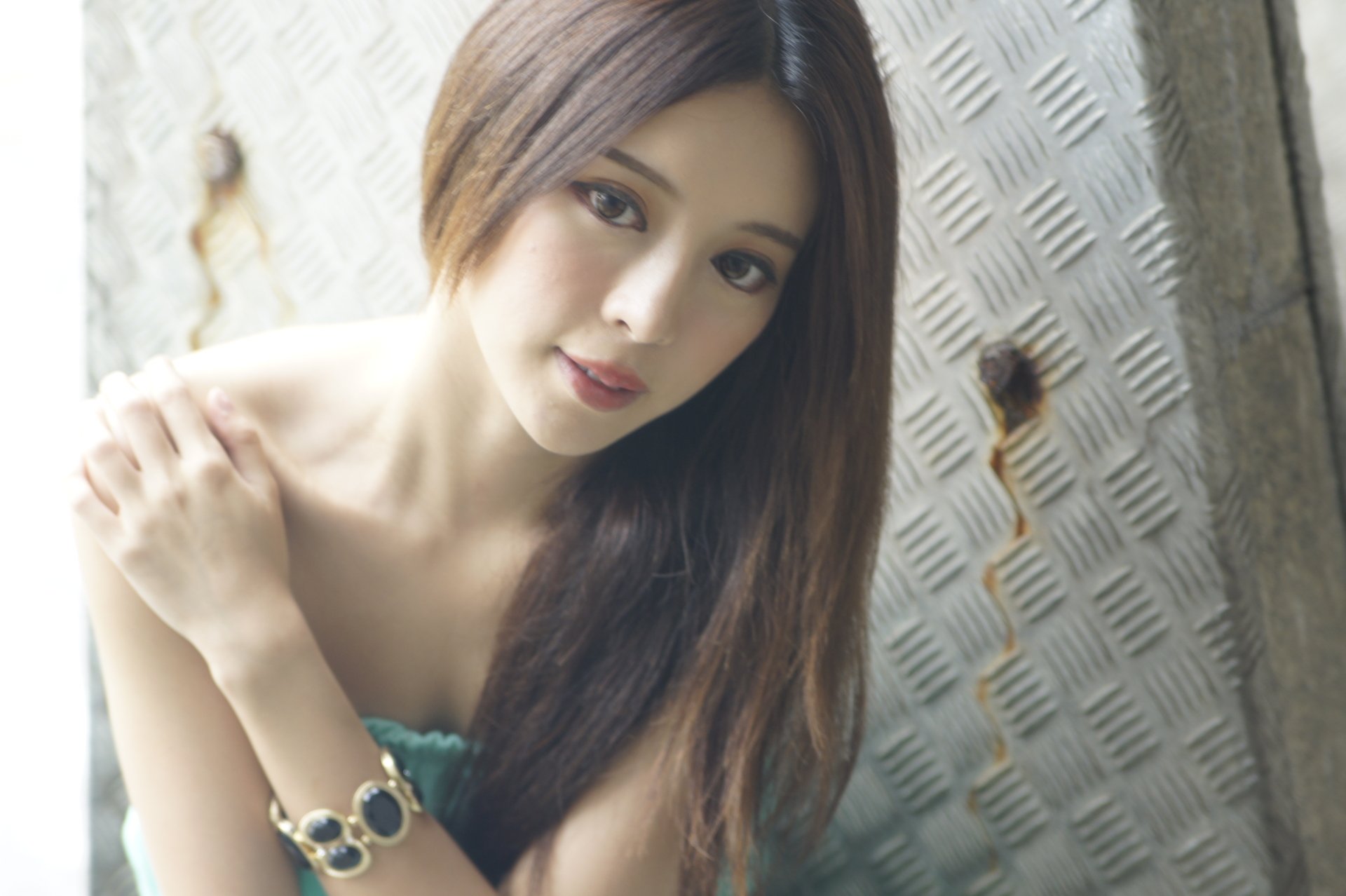 Portrait of Taiwanese model Julie Chang wearing a bracelet against a textured metal background with soft bokeh, featured in a 4K Ultra HD desktop wallpaper.