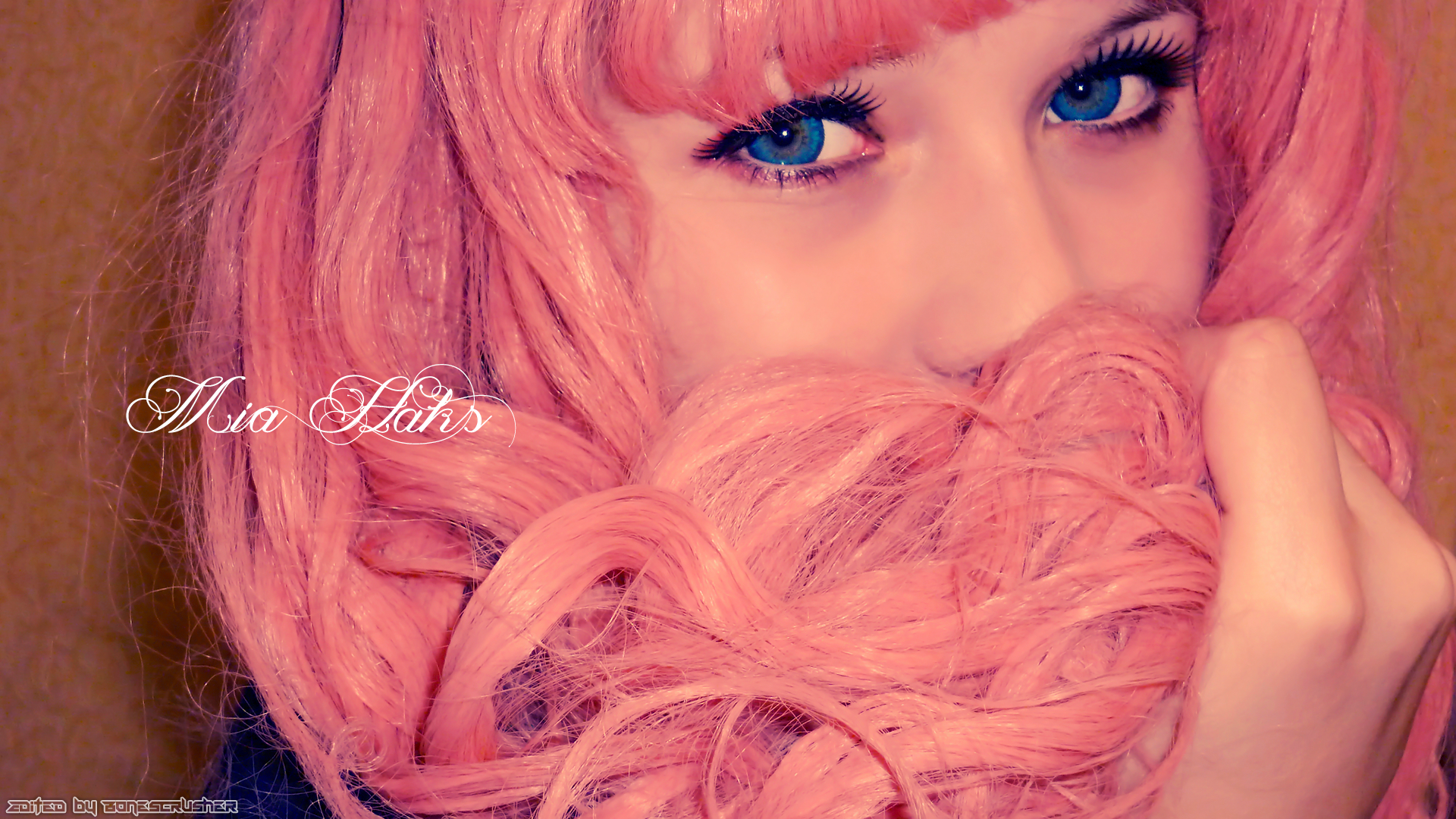 Close-up HD desktop wallpaper of Mia Haks in pink cosplay wig, showcasing bright blue eyes and soft pink hair details.