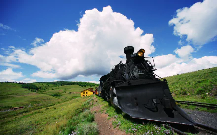 HD desktop wallpaper featuring a vintage train on tracks in a lush countryside landscape under expansive cloudy skies.