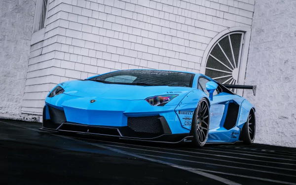 HD desktop wallpaper featuring a stunning blue Lamborghini Aventador LP700-4 supercar parked in front of a white brick wall with an arched window.