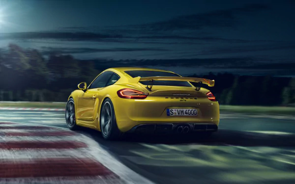 Yellow Porsche Cayman GT4 speeding on a racetrack at dusk, captured in high definition as a dynamic PC desktop wallpaper.
