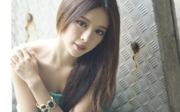 Portrait of Taiwanese model Julie Chang wearing a bracelet against a textured metal background with soft bokeh, featured in a 4K Ultra HD desktop wallpaper.