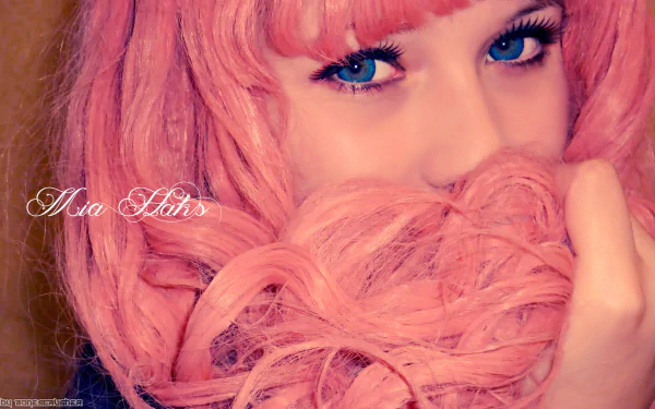 Close-up HD desktop wallpaper of Mia Haks in pink cosplay wig, showcasing bright blue eyes and soft pink hair details.