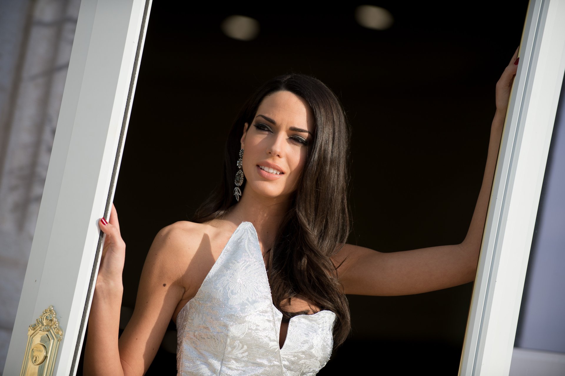 4K Ultra HD portrait of a model with long dark hair in an elegant white dress, posed in a doorway — PC desktop wallpaper.