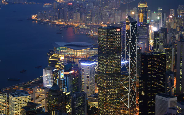 Night view of Hong Kong's megapolis along Victoria Harbour, illuminated skyscrapers reflecting the vibrant man-made cityscape in 4K Ultra HD quality.