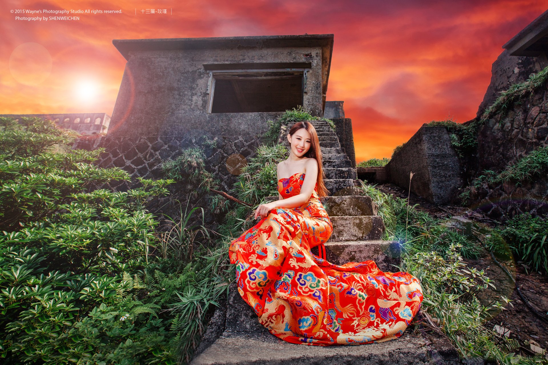 An Asian woman in a vibrant red dress poses gracefully on stone steps of a ruin, with a captivating sunset in the background. The HD wallpaper exudes a serene and mystical atmosphere.