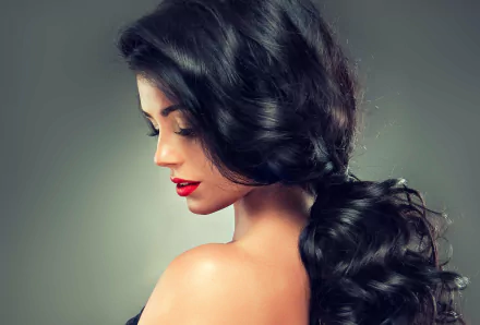 Close-up of a woman model with voluminous, dark hair styled in loose waves, showcasing her face and shoulder, captured in 4K Ultra HD quality for a PC desktop wallpaper.