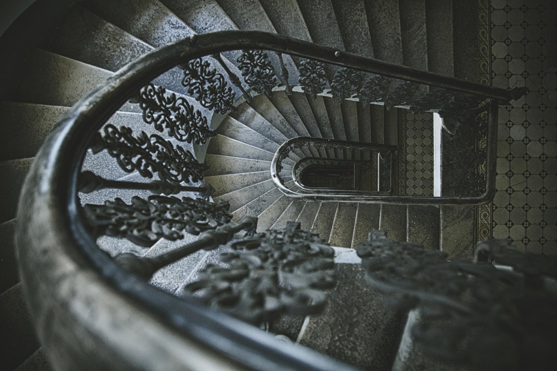 Aerial view of a man-made spiral staircase with ornate wrought-iron railing and moody lighting, presented as an HD PC desktop wallpaper and background.