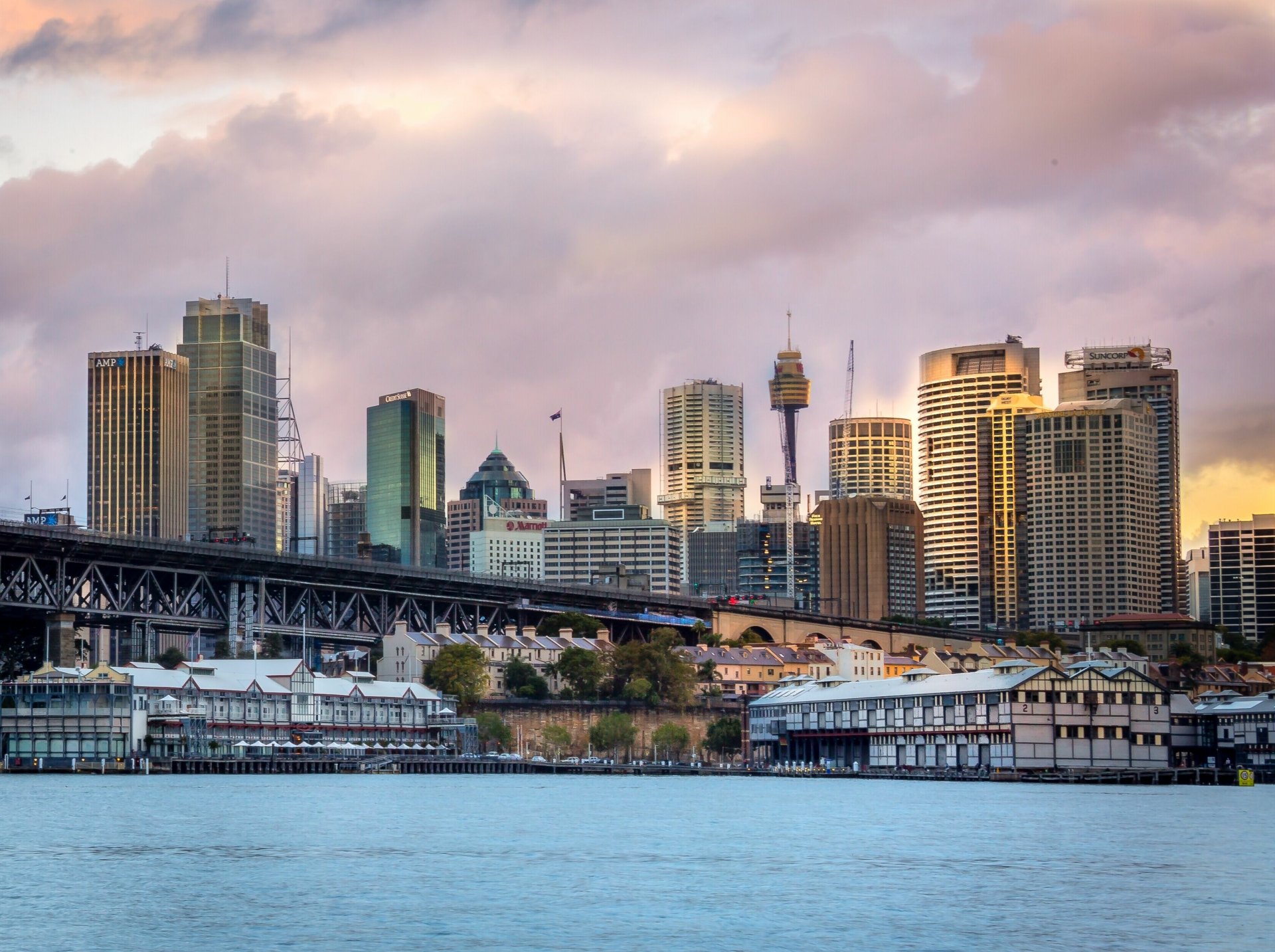 Man-made Sydney skyline at golden hour with Harbour Bridge and waterfront buildings — 2K Quad HD PC desktop wallpaper and background.