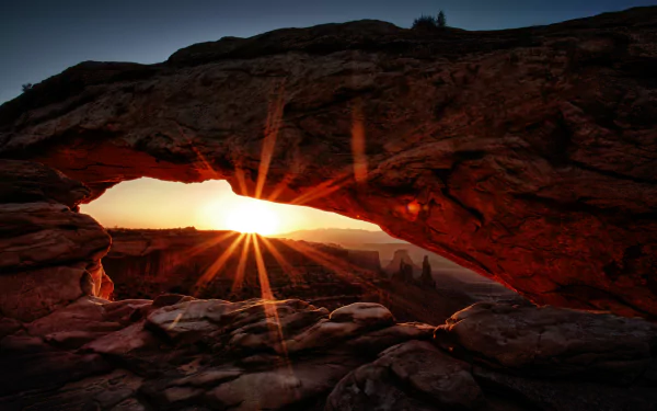 Sunrise through Mesa Arch framing desert spires, glowing orange rock and starburst sun - 5K Ultra HD PC desktop wallpaper/background