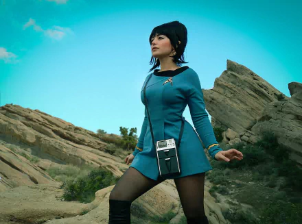 A woman in cosplay stands confidently in a rocky outdoor setting. The HD image serves as a vibrant desktop wallpaper and background.