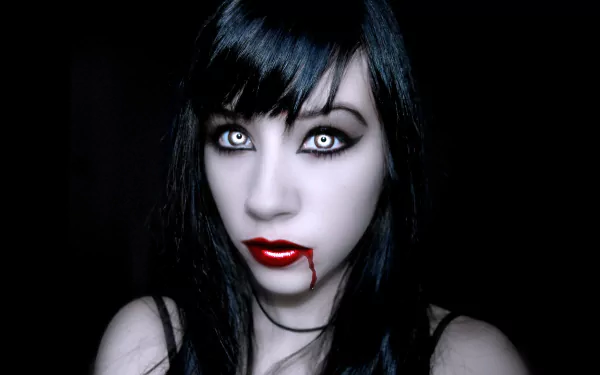 A striking HD desktop wallpaper featuring a dark vampire with long black hair, intense gray eyes, and blood-red lips, set against a deep black background.