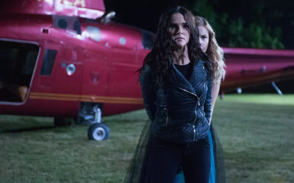 Vampire Academy movie 2K Quad HD PC wallpaper: two women stand tense before a red helicopter at night in a dramatic, low‑light action scene.