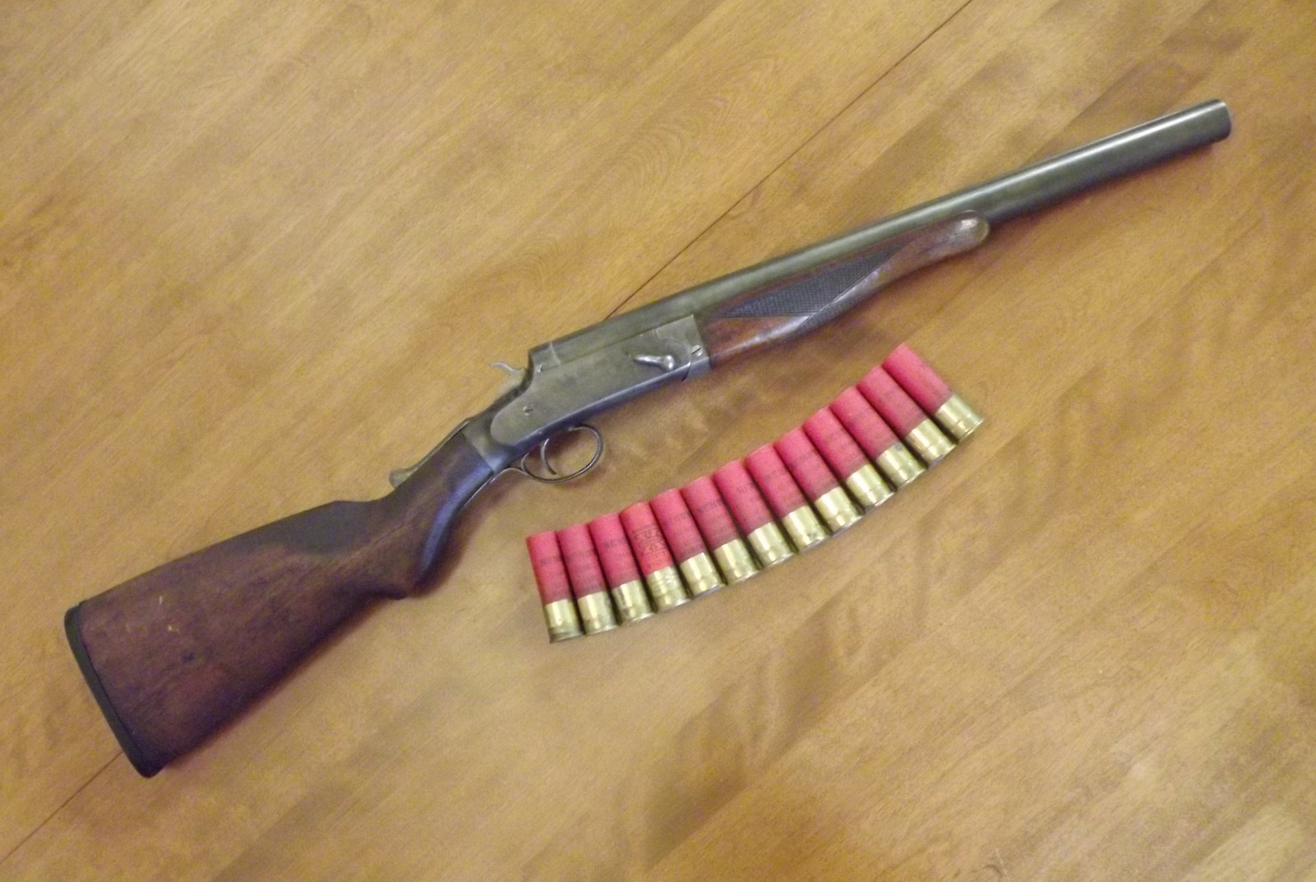 4K Ultra HD desktop wallpaper featuring a man-made shotgun with wooden stock and a row of red shotgun shells on a wooden surface.