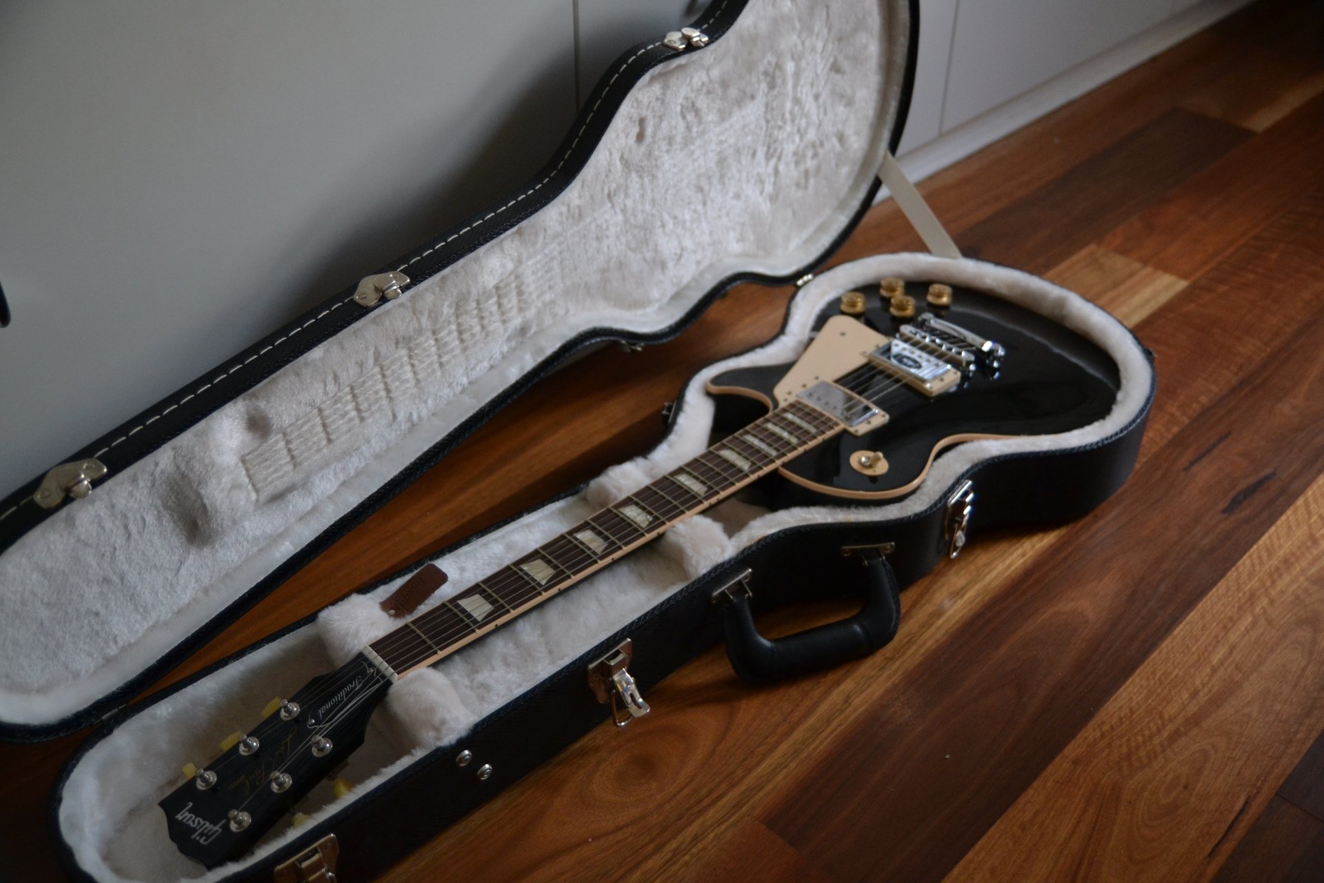 4K Ultra HD PC desktop wallpaper: electric guitar in open hardshell case on a hardwood floor, close-up of fretboard and pickups — music, guitar.