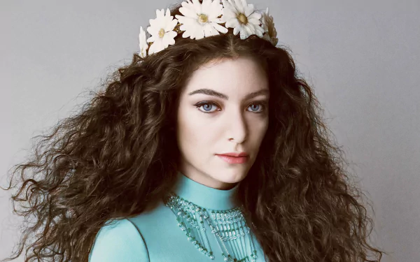 HD PC desktop wallpaper of a music artist with long curly hair, daisy crown and teal dress, posed against a soft gray background.