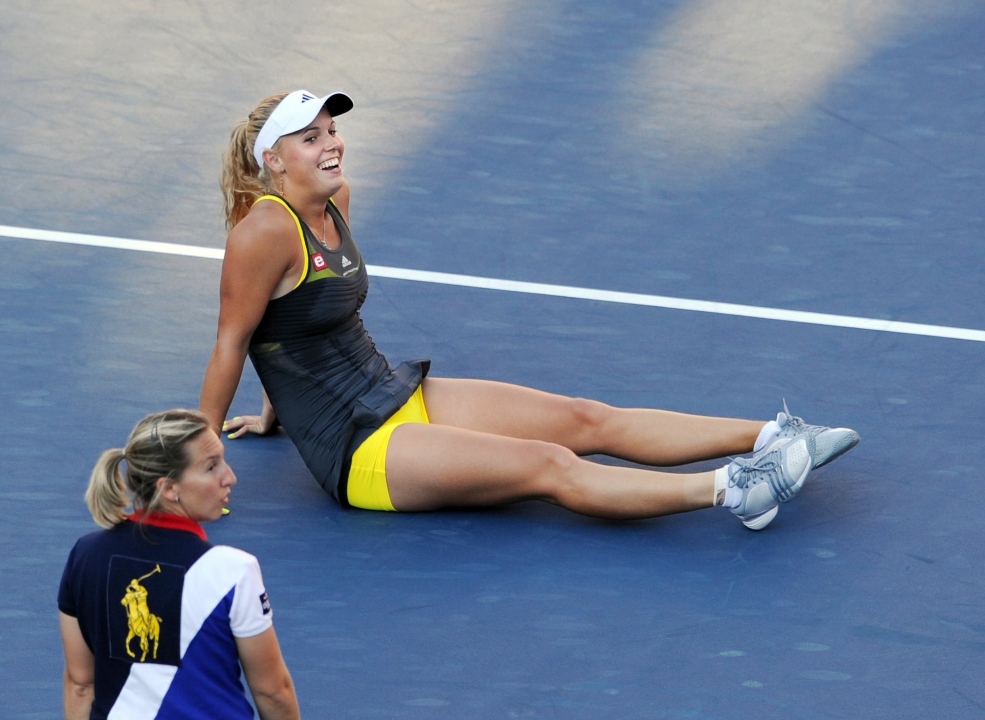 Caroline Wozniacki sits on a tennis court during a match, smiling and dressed in athletic wear, captured in a high-definition sports-themed desktop wallpaper.