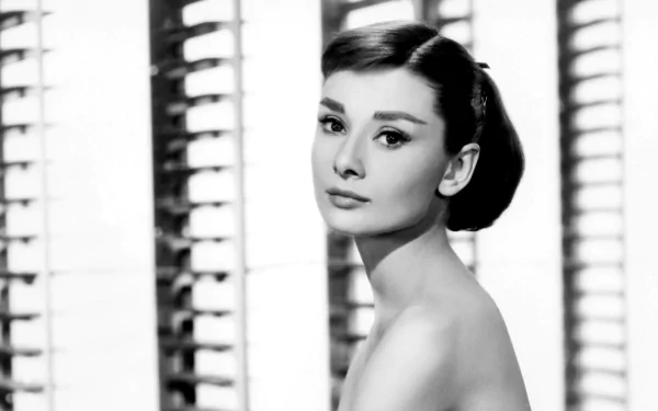 Black-and-white HD PC desktop wallpaper: elegant 1950s Hollywood–style studio portrait of a young woman with a sleek updo, winged eyeliner and bare shoulders posed before blinds.