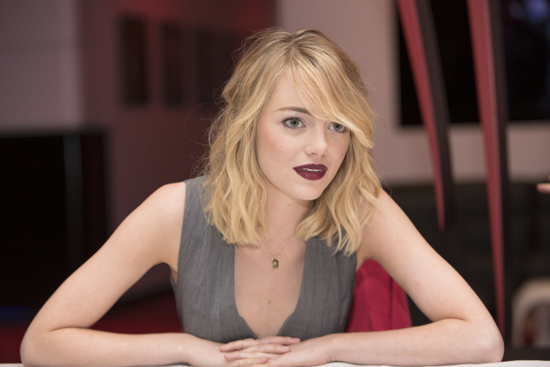 4K Ultra HD image of celebrity Emma Stone with blonde hair and dark lipstick, set against a blurred indoor background, designed as a PC desktop wallpaper.