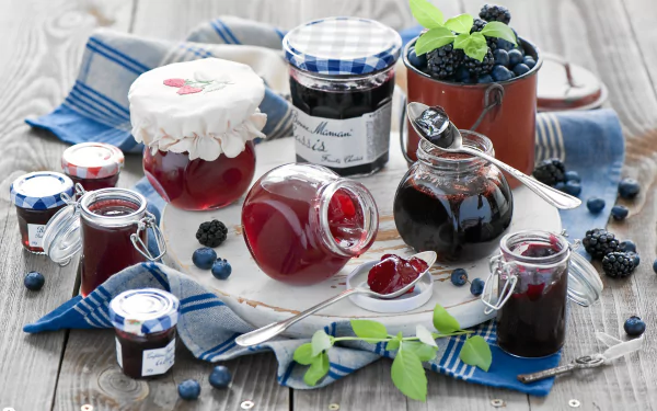 HD desktop wallpaper featuring an assortment of jam jars and fresh berries on a rustic wooden table with blue checkered cloths.