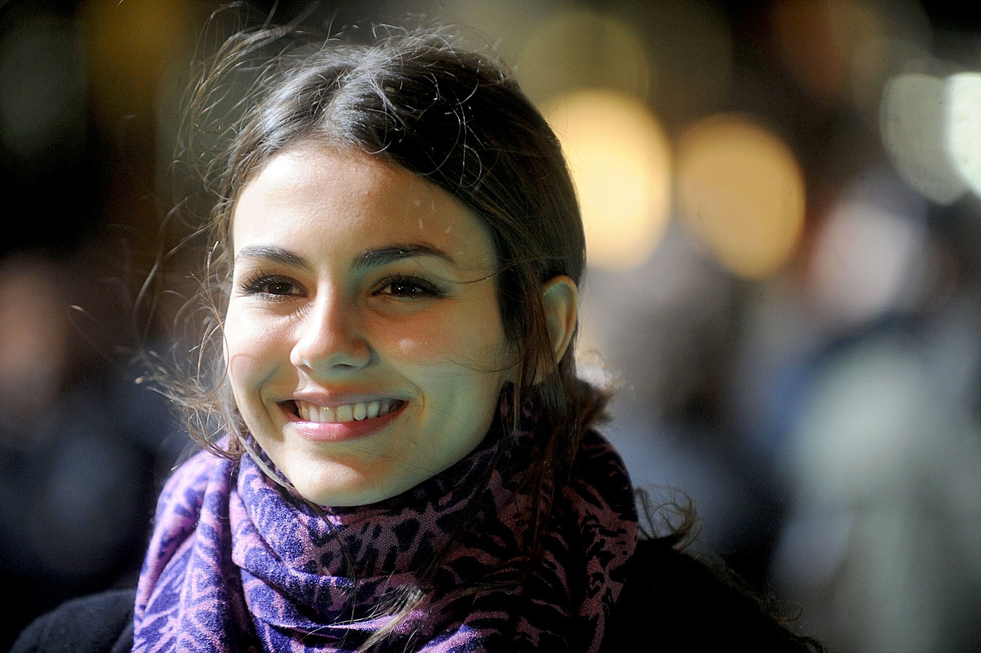 HD PC desktop wallpaper featuring a close-up of celebrity Victoria Justice smiling softly with blurred lights in the background.