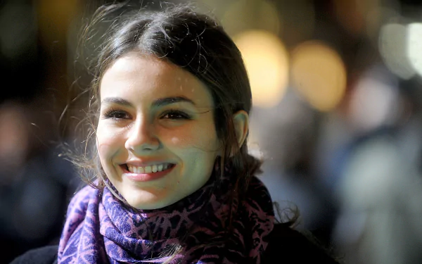 HD PC desktop wallpaper featuring a close-up of celebrity Victoria Justice smiling softly with blurred lights in the background.