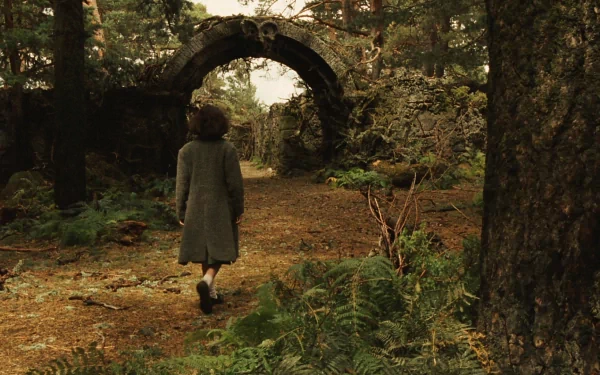 HD PC desktop wallpaper from the movie Pan's Labyrinth showing a child walking toward an ancient stone arch in a dense, forested area.