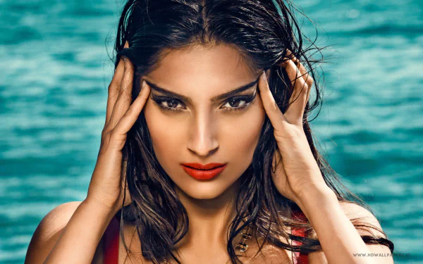HD desktop wallpaper and background featuring celebrity Sonam Kapoor with a focused expression, wet hair, and vibrant makeup, set against a serene ocean backdrop.