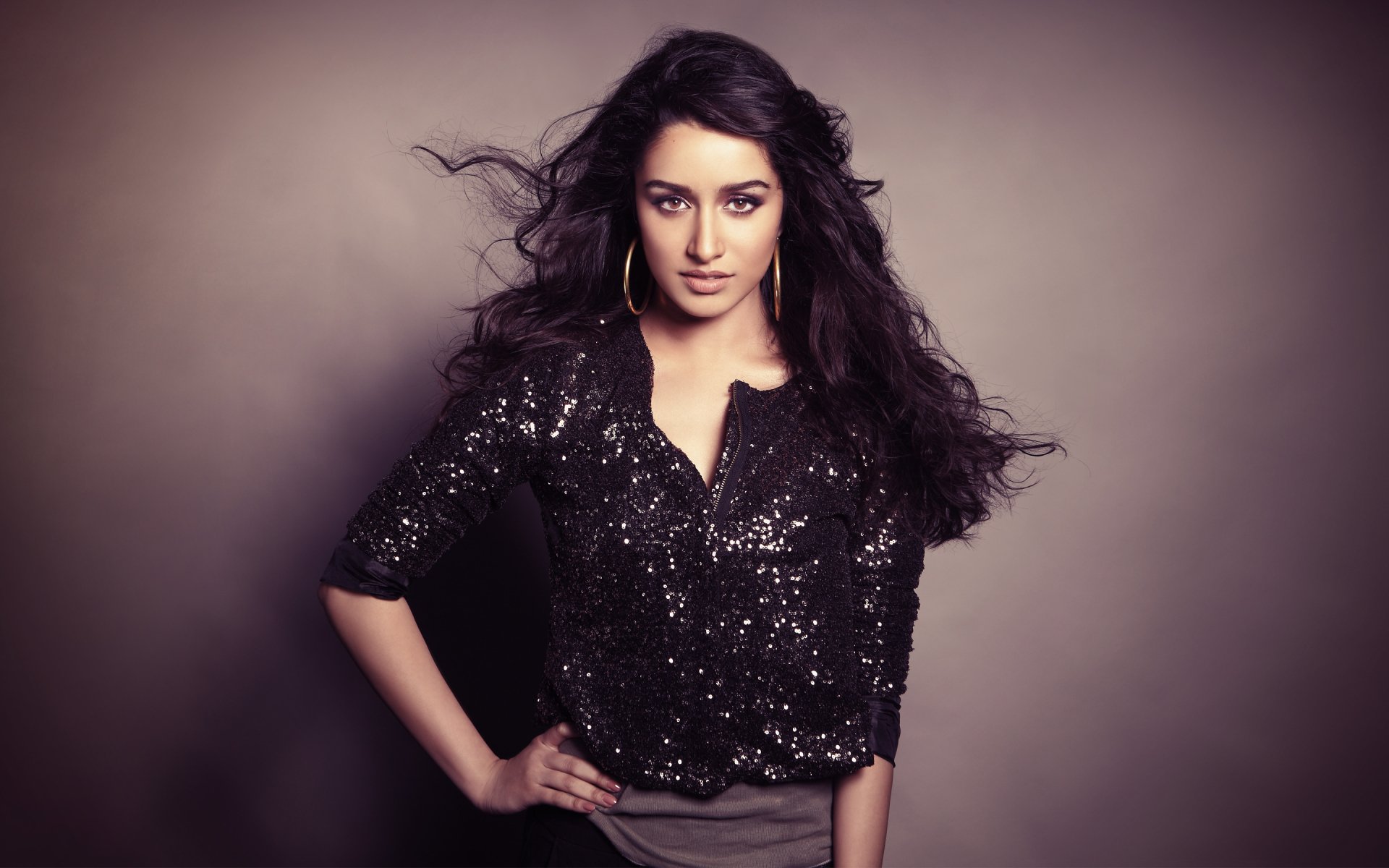 A stylish Shraddha Kapoor poses confidently in a shimmering black outfit, set against a soft gradient backdrop, creating an eye-catching HD desktop wallpaper.