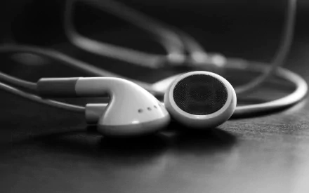 A close-up of white headphones resting on a dark surface, creating a striking contrast. This HD PC desktop wallpaper captures the essence of music and sound.