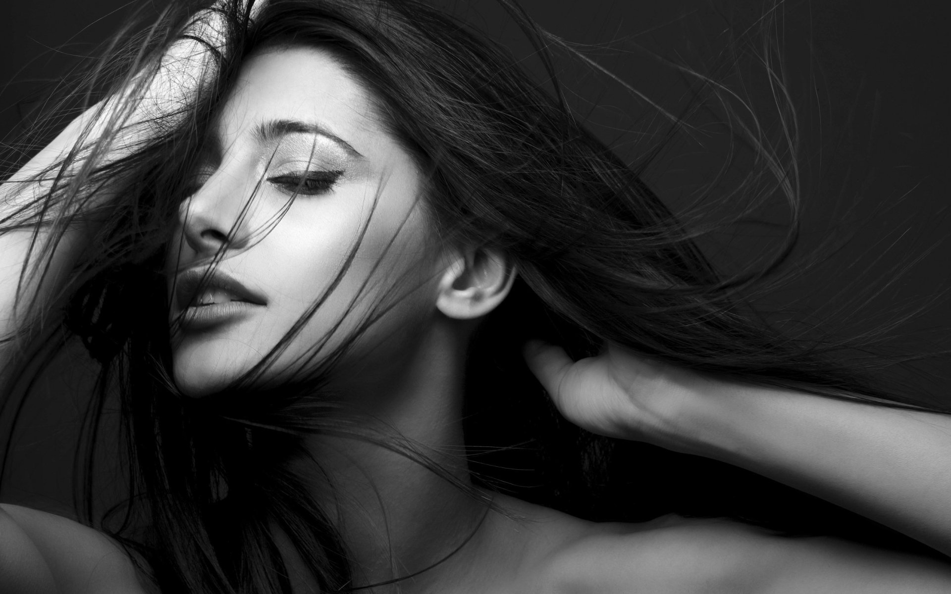 Black-and-white close-up of a female celebrity with windswept hair and a serene expression, elegant profile — 2K Quad HD PC desktop wallpaper and background.