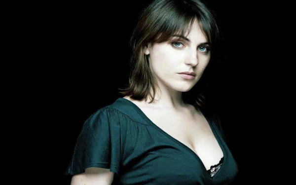 HD desktop wallpaper featuring a close-up portrait of woman Antje Traue with dark hair and striking eyes against a plain background.