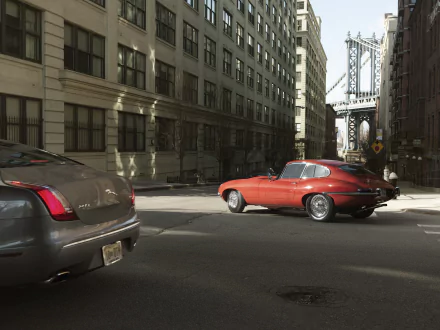 Red Jaguar E-Type parked on an urban street with city buildings and a bridge in the background, captured in stunning 4K Ultra HD detail for a PC desktop wallpaper.