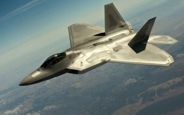 A Lockheed Martin F-22 Raptor soars through a clear blue sky, showcasing its advanced design and military prowess. High-definition wallpaper featuring this iconic fighter jet.