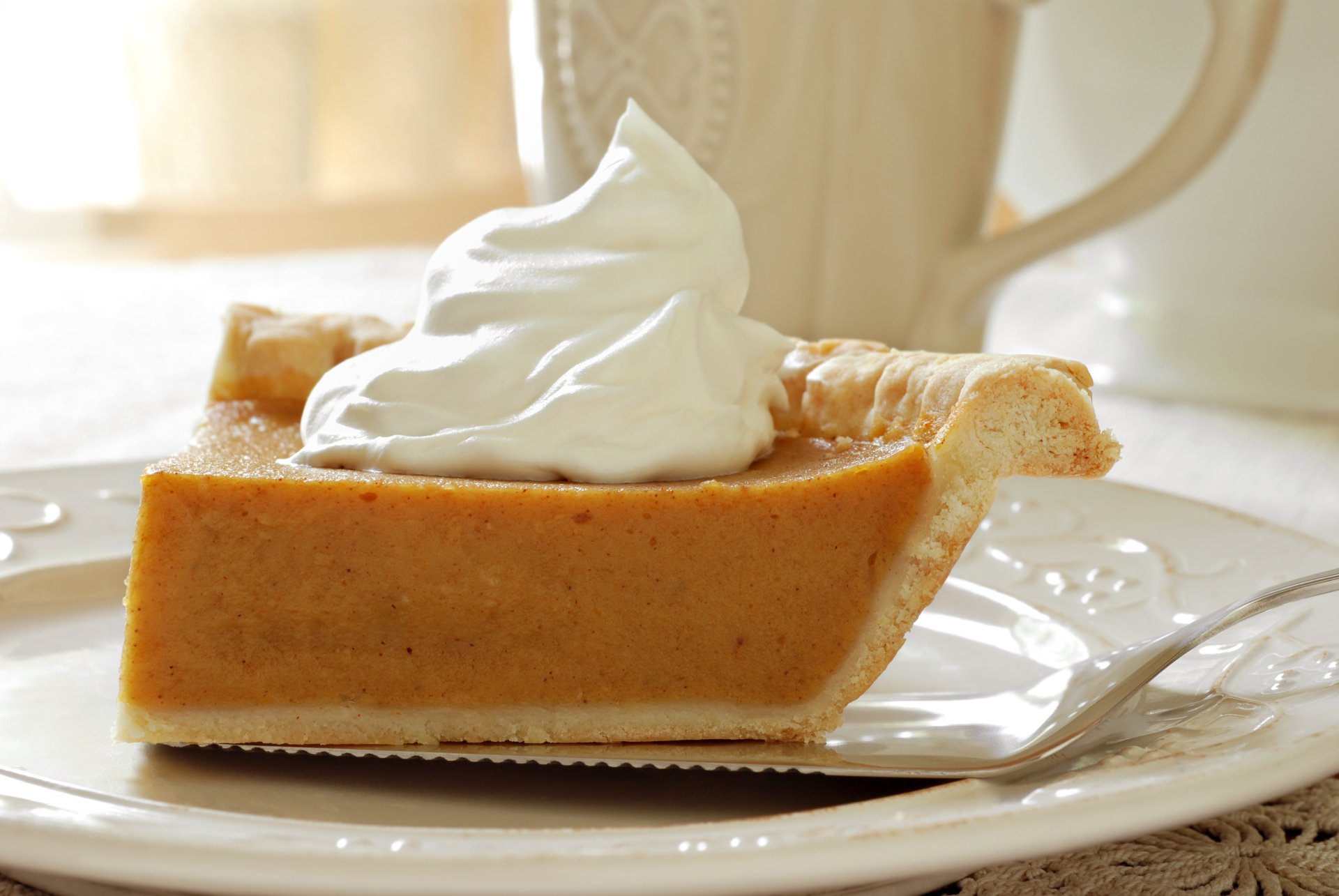 A slice of creamy pumpkin pie topped with whipped cream on a white plate, captured in 4K Ultra HD for a vibrant PC desktop wallpaper.
