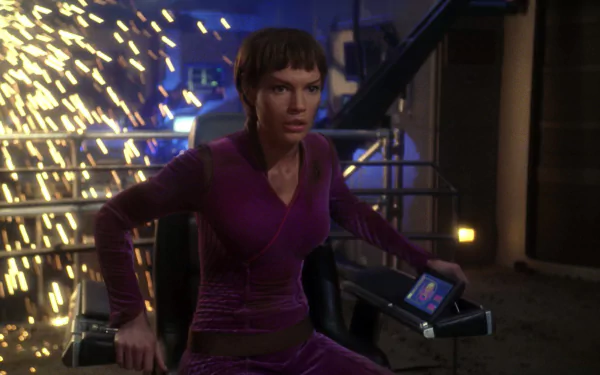 Jolene Blalock as T'Pol in Star Trek: Enterprise captured in an HD desktop wallpaper, set against a dynamic industrial backdrop with sparks flying.