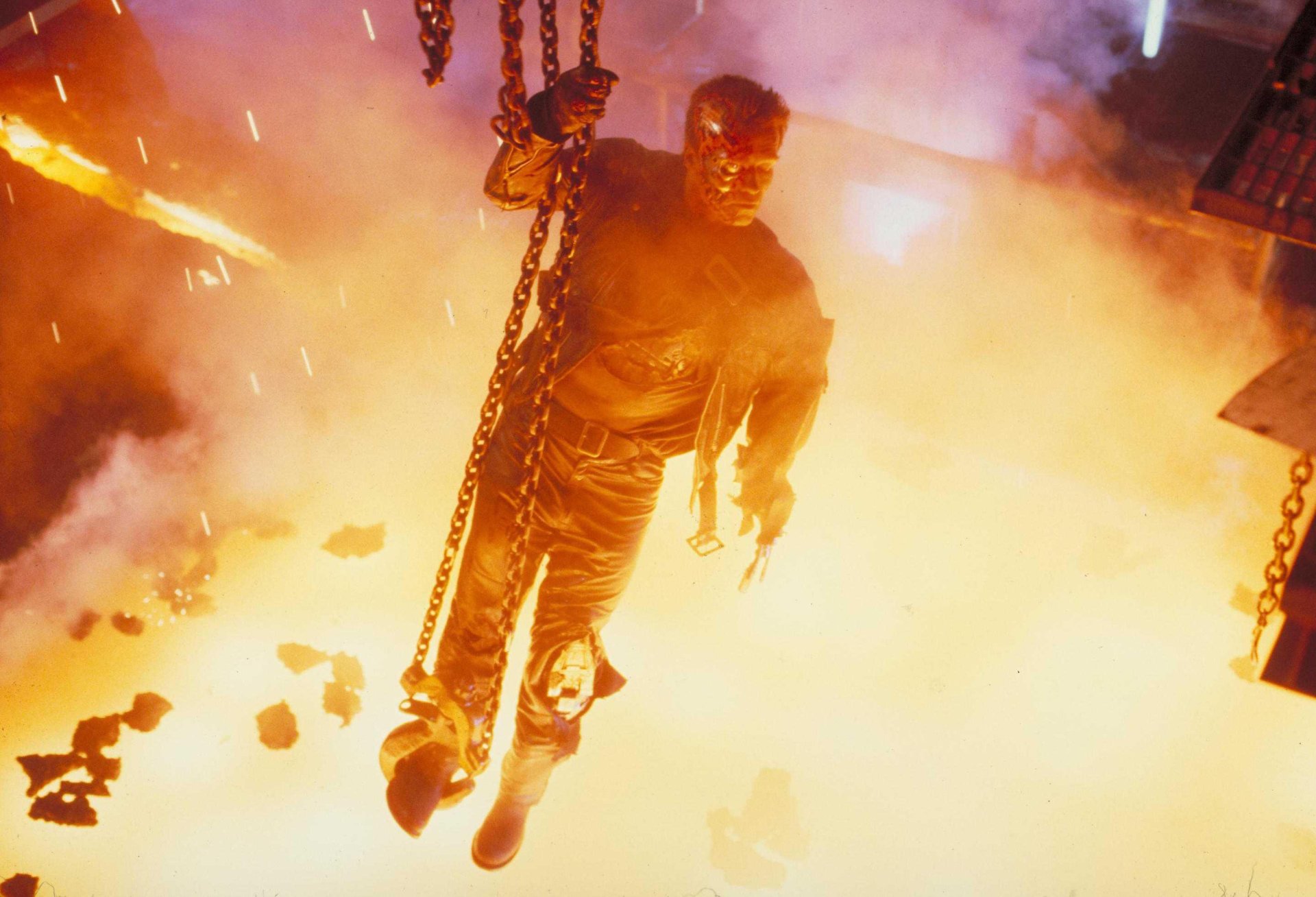 A dramatic scene from Terminator 2: Judgment Day, featuring Arnold Schwarzenegger amidst explosions and chaos, captured in high-definition for a striking desktop wallpaper.
