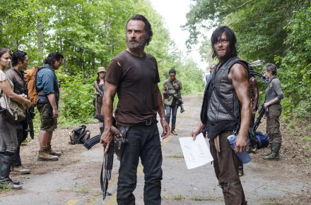 HD desktop wallpaper featuring Rick Grimes and the cast of The Walking Dead, depicting a tense moment in a forest clearing from the TV show.
