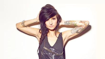 A woman with striking tattoos poses confidently against a light background, showcasing her unique style. This HD image makes a bold statement for desktop wallpaper.
