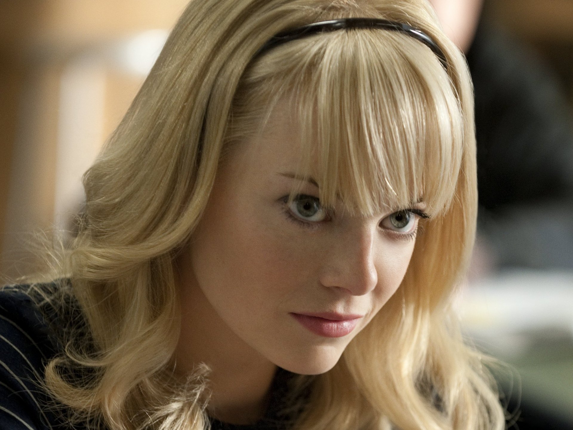 HD desktop wallpaper featuring Emma Stone from the movie The Amazing Spider-Man, showcasing a close-up of her face with blonde hair and an intense gaze.